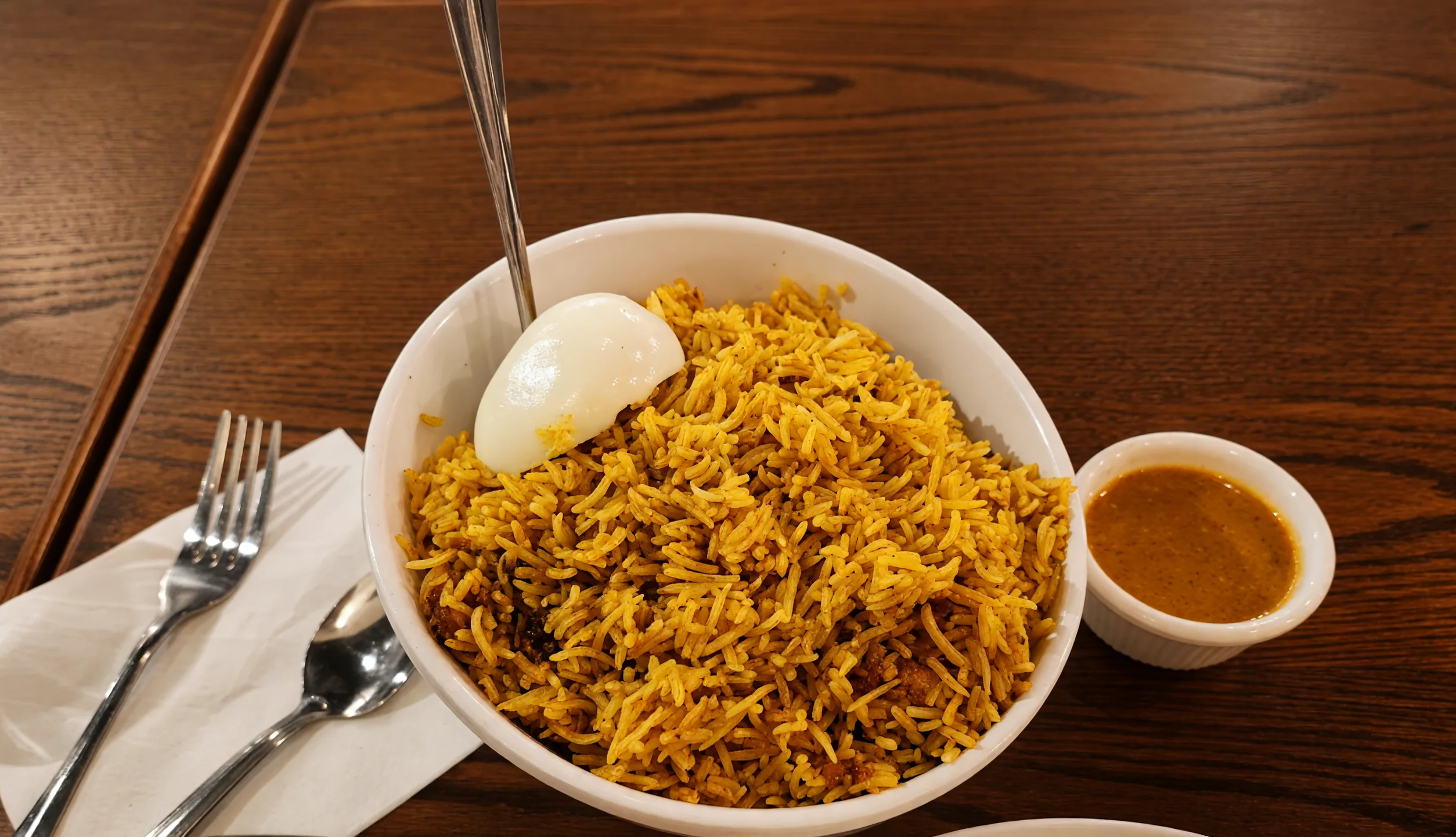 Hyderabadi chicken dum biryani with a boiled egg and a cup of salan at Bawarchi in Mississauga