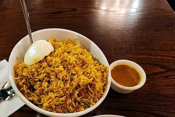 Hyderabadi chicken dum biryani with a boiled egg and a cup of salan at Bawarchi in Mississauga